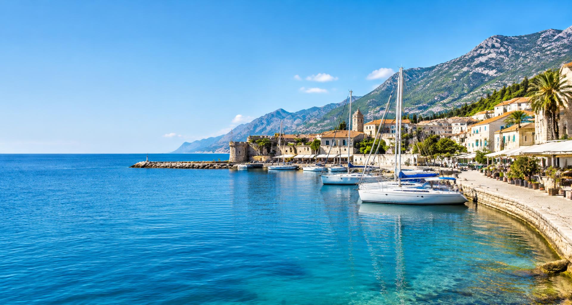 A sunlit Mediterranean harbour with sailing boats